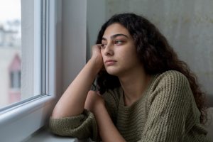 Sad young woman looks out of window