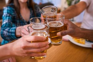 Close up on drinks held by diverse friends toasting during the dinner.